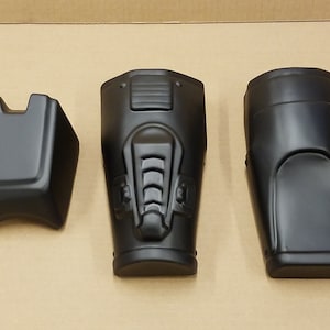 Pode incluir: Três carenagens de motocicleta de plástico preto. As carenagens são de diferentes formas e tamanhos.