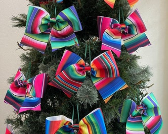 May include: A Christmas tree decorated with colorful striped bows. The bows are made of fabric and have a traditional Mexican serape pattern.