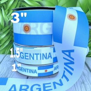 May include: Three rolls of blue and white ribbon featuring the Argentinian flag and the word "Argentina" printed on them. The ribbon is 3 inches, 1.5 inches, and 1 inch wide.
