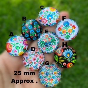 May include: Eight round, colorful, decorative, wooden ornaments with a folk art design. The ornaments are approximately 25 mm in diameter. The designs feature flowers, birds, and geometric patterns.