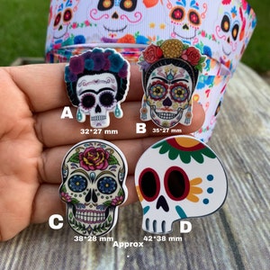 May include: Four sugar skull-themed resin cabochons in various sizes. The cabochons are decorated with colorful floral patterns and have black eyes. The cabochons are labeled A, B, C, and D with their approximate dimensions in millimeters.