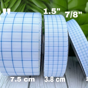 May include: Three rolls of white ribbon with blue grid pattern. The ribbon widths are 3 inches, 1.5 inches, and 7/8 inches. The ribbon widths are also shown in centimeters: 7.5 cm, 3.8 cm, and 2.2 cm.