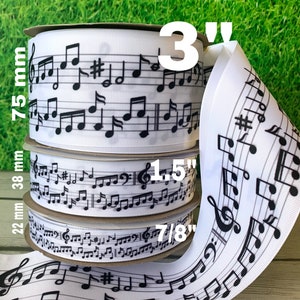 May include: White ribbon spools with black musical notes. The largest spool is 3 inches wide (75 mm), the middle spool is 1.5 inches wide (38 mm), and the smallest spool is 7/8 inches wide (22 mm). The ribbon is ideal for crafting and music-themed projects.