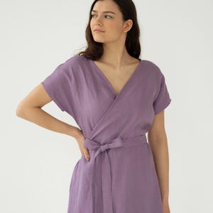 Peut inclure: Une robe portefeuille lavande avec des manches courtes et une ceinture assortie. La robe présente un col en V et une jupe mi-longue. Le tissu semble être du lin léger ou une matière similaire, adaptée aux climats chauds.