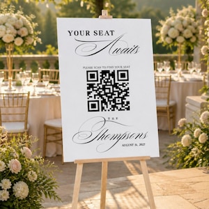 May include: A white rectangular wedding seating chart sign on a wooden easel. The sign features black text reading YOUR SEAT AWAITS, PLEASE SCAN TO FIND YOUR SEAT, THE Thompsons, and AUGUST 31, 2027, centered around a large black and white QR code.