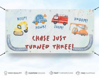 May include: A blue, red, and yellow birthday banner with a road and construction vehicles. The banner says "Chase Just Turned Three!" with the words "Beep!", "Honk!", "Zoom!" and "Vroom!" on it.