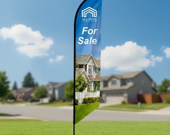 May include: A blue real estate flag with the words "For Sale" in white. The flag features a house graphic and a photo of a house. The flag is displayed on a green lawn with houses in the background.