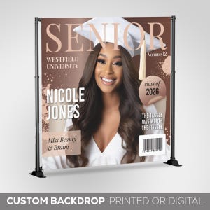 May include: A graduation backdrop featuring a magazine cover design with a photo of a woman in a cap and gown. The magazine cover reads "Senior" and "Nicole Jones" with the text "Westfield University" and "Class of 2026".