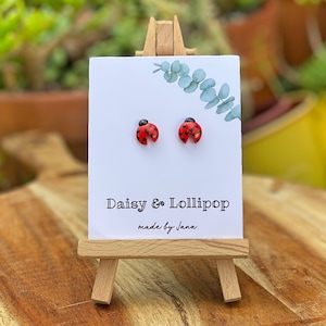 May include: A pair of ladybug stud earrings on a white card with the text "Daisy & Lollipop made by Jana".