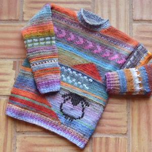 Könnte beinhalten: Ein bunter Strickpullover mit einem mehrfarbigen Streifenmuster und einem kleinen Schafdesign auf der Vorderseite.