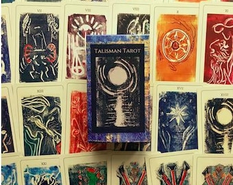 May include: A deck of Talisman Tarot cards with a blue and white box. The cards are illustrated with black and white images on a cream background. The box has the text "Talisman Tarot" printed on the front.