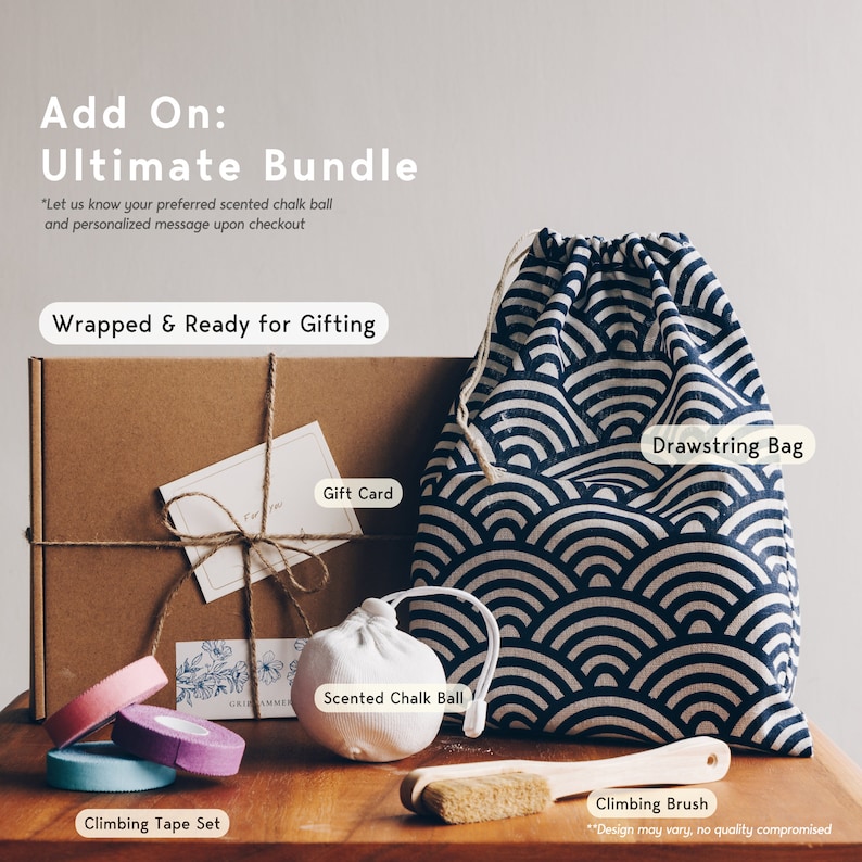 May include: A climbing bundle featuring a brown cardboard gift box with twine, a white gift card, a navy and white wave-patterned drawstring bag, a white scented chalk ball, a wooden climbing brush, and three rolls of climbing tape in pink, purple, and blue.
