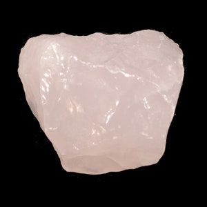 May include: A large, pale pink, rough-hewn rose quartz crystal.