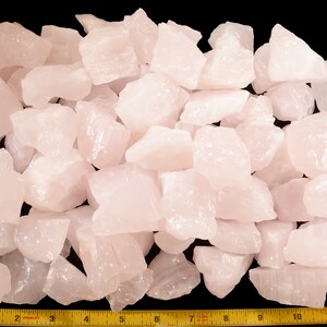 May include: A large pile of pale pink rose quartz crystals, measuring approximately 12 inches across. The crystals are rough and have a natural, unpolished appearance.