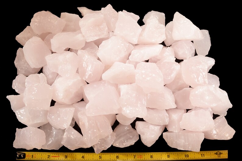 May include: A large pile of pale pink rose quartz crystals, measuring approximately 12 inches across. The crystals are rough and have a natural, unpolished appearance.
