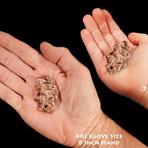May include: Two hands holding a large, irregular, copper-colored rock. The hand on the left is an adult hand with an 8 inch circumference. The hand on the right is a child's hand, belonging to a 7 year old.