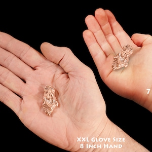 May include: Two hands holding a copper nugget. The hand on the left is an adult hand with an 8 inch circumference. The hand on the right is a child's hand, belonging to a 7 year old.