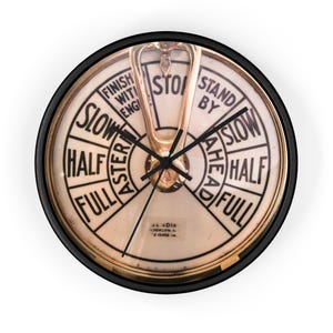 Può includere: Un orologio nero e dorato con un design a ruota di nave. Il quadrante dell'orologio ha le parole "Slow", "Half", "Full", "Stand By", "Ahead" e "Stop" stampate su di esso. L'orologio è realizzato da Bendix Brooklyn N.Y. 13402 LA.