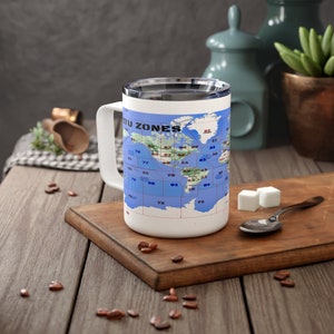 May include: White travel mug with a blue and green world map printed on it. The map shows the International Telecommunication Union (ITU) time zones. The mug has a black handle and a silver lid.