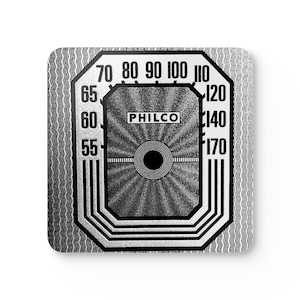 Op de afbeelding: Een zwart-witte vintage radio-wijzerplaat met het woord "PHILCO" in het midden. De wijzerplaat heeft nummers van 55 tot 170.