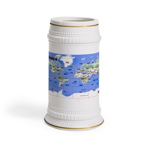 May include: White ceramic beer stein with a gold rim and a world map design. The map is blue with green landmasses and shows time zones.