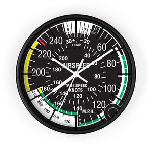 May include: Black and white aircraft instrument with a green and yellow dial. The dial reads "airspeed" and shows knots and miles per hour. The instrument has a black bezel and a white needle.
