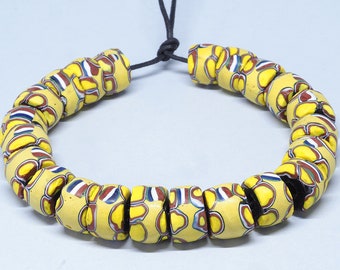 May include: A necklace made of yellow, red, blue, and white glass beads. The beads are cylindrical and have a swirling pattern. The necklace is strung on a black cord.