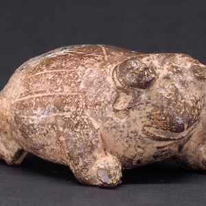 May include: A ceramic frog figurine in shades of brown and tan. The frog has a textured surface with visible details, including eyes, legs, and a slightly open mouth. The figurine is a decorative item.