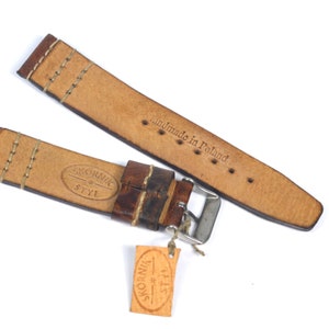 May include: Brown leather watch strap with white stitching and a silver buckle. The strap is labeled "Sk&oacute;rnik Styl" and "handmade in Poland".