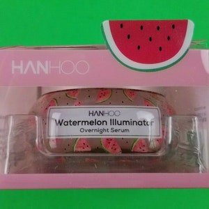May include: A pink and clear plastic container of watermelon-scented overnight serum. The container has a watermelon design and the text "HANHOO Watermelon Illuminator Overnight Serum" on the front.