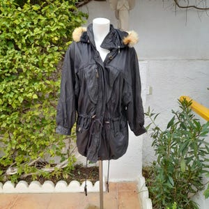 May include: Black leather jacket with a fur-trimmed hood. The jacket features a drawstring waist, multiple pockets, and a zipper closure. The jacket is displayed on a mannequin.