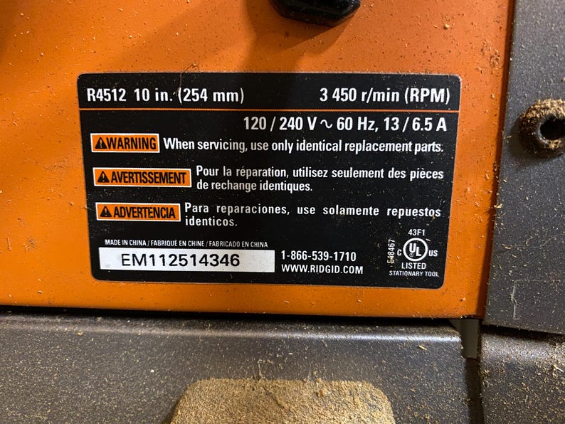 May include: Close-up of a black and orange power tool with a label. The label includes the model number R4512, 10 in. (254 mm), and other specifications. It also has a warning about using identical replacement parts.