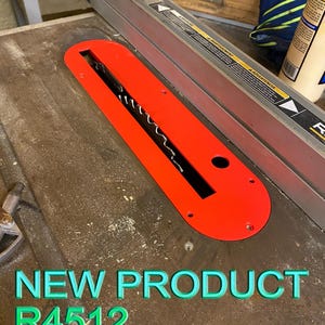 May include: A bright red table saw insert with a black blade opening. The insert is labeled "R4512" and "NEW PRODUCT" in green text. The saw is on a wooden surface.
