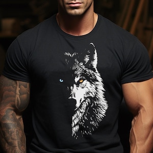 May include: Black crew neck t-shirt featuring a detailed white and black wolf graphic. The wolf's eyes are a striking blue and yellow. The shirt is worn by a person with tattoos and a watch.