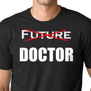 May include: Black t-shirt with white text that says "FUTURE DOCTOR" with a red line crossed out over the word "FUTURE".