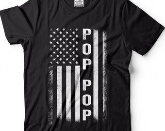 May include: Black t-shirt with a white distressed American flag design. The word "POP" is vertically printed on the flag.