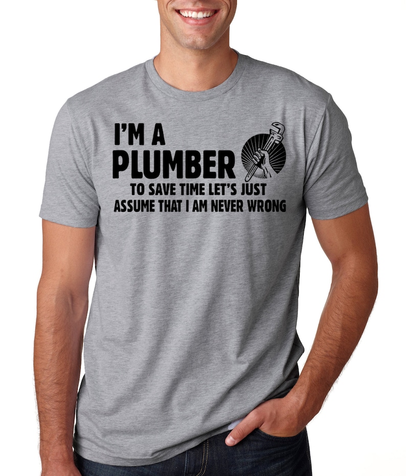 May include: A gray t-shirt with the text "I'M A PLUMBER TO SAVE TIME LET'S JUST ASSUME THAT I AM NEVER WRONG" in black. The shirt also features a graphic of a hand holding a wrench.