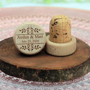 Personalized wine stopper engraved number 5 design, perfect for rustic style weddings, wedding favors and wedding party favors, made of wood and cork, on a wooden base with decorative flowers. An excellent gift for guests and decoration for weddings.