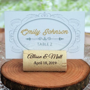 Personalized engraved horizontal wine cork, number 6 design, used for rustic wedding place cards, wedding place holder, parties and table decoration. on a wooden base with decorative flowers. Gift for guests, beautiful decoration for weddings.