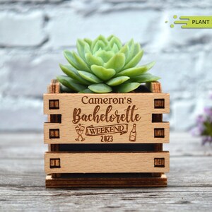 May include: Wooden planter box with the text "Cameron's Bachelorette Weekend 2023" and a small succulent plant inside.