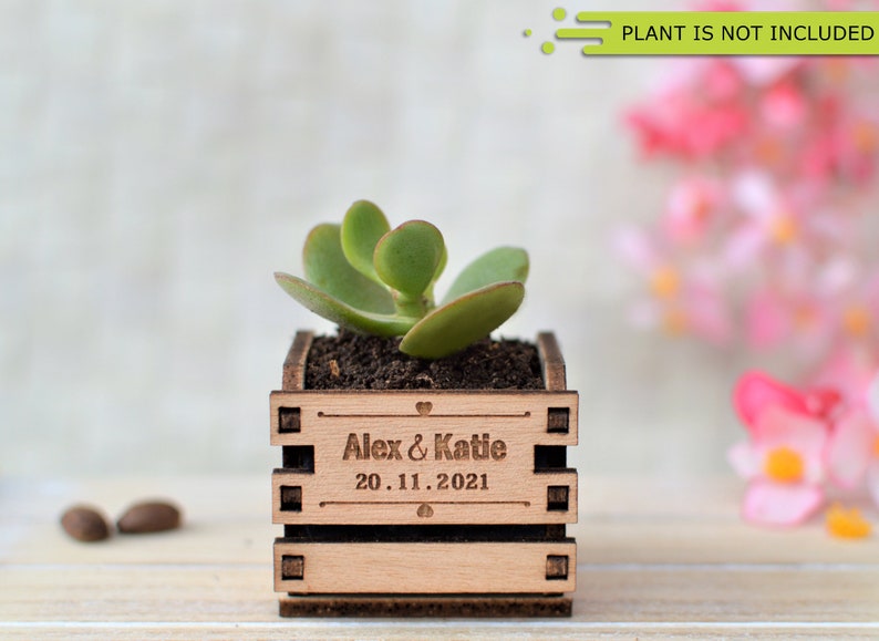 Engraved personalized mini pots, used for wedding favors, rustic style wedding decorations and your home. It is made of wood, with a succulent plant on a wooden table decorated with flowers. An excellent gift for guests and all your loved ones.