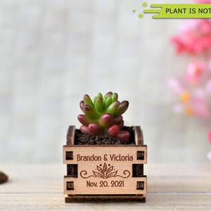 Engraved personalized mini pots, used for wedding favors, rustic style wedding decorations and your home. It is made of wood, with a succulent plant on a wooden table decorated with flowers. An excellent gift for guests and all your loved ones.