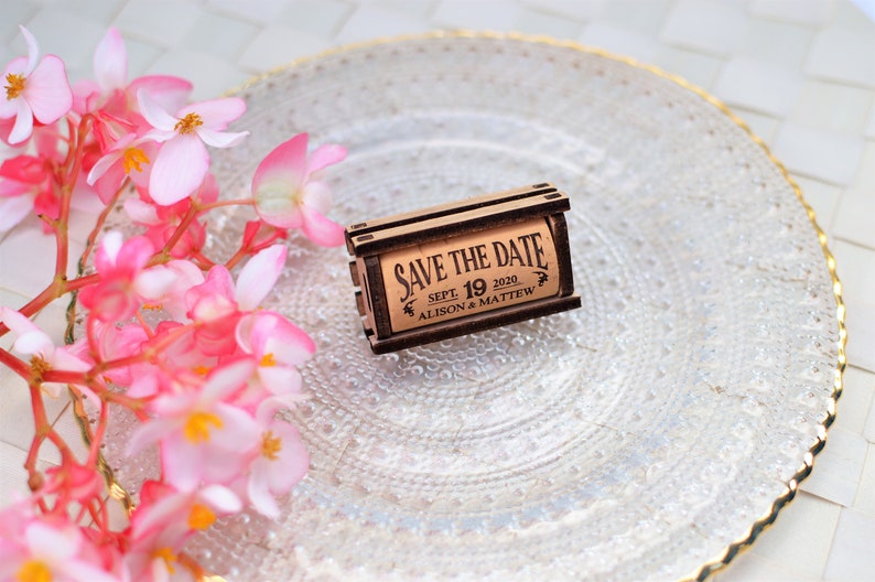 Personalized Save the Date corks for wine with wooden box and with or without magnets, used in wine themed weddings, and rustic weddings. It is made of 100% Natural High Quality Cork. On a glass plate with decorative flowers.