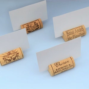 Cork card holder from different vineyards. Used for rustic wedding cards, wedding booths, anniversaries, parties and table decorations. on a wooden base with decorative flowers. for wedding favors