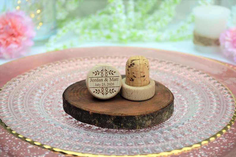 Personalized wine stopper engraved number 5 design, perfect for rustic style weddings, wedding favors and wedding party favors, made of wood and cork, on a wooden base with decorative flowers. An excellent gift for guests and decoration for weddings.
