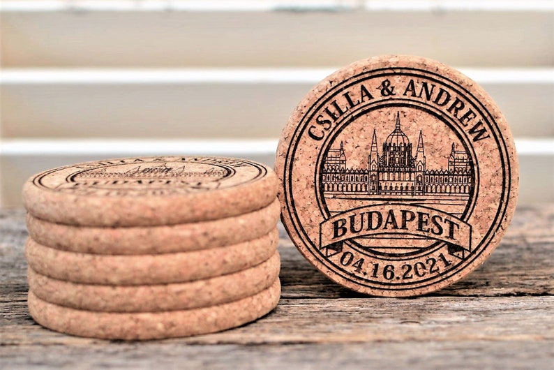 Personalized engraved cork coasters Budapest design, used for rustic wedding decorations, wedding favors and parties. They are made of high quality natural cork. On a wooden table. An excellent gift for guests and loved ones.