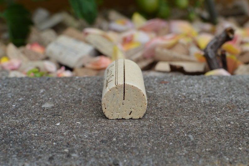 Personalized Cork Place Card Holder, Laser Engraved. Used for Rustic Wedding Place Cards, Wedding Booth, Parties and Table Decorations. on a wooden base with decorative flowers. for wedding favors