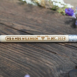 Personalized mini golf pencils, used for wedding favors and decorations at country style wedding, with white eraser, on wooden table with decorative flowers. An excellent gift for guests and all your loved ones.