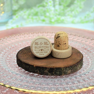 Personalized wine stopper, laser engraved, design 3, perfect for decorating rustic style weddings, parties and anniversaries. Made of wood and cork, on a table with decorative flowers. An excellent wedding favor for guests