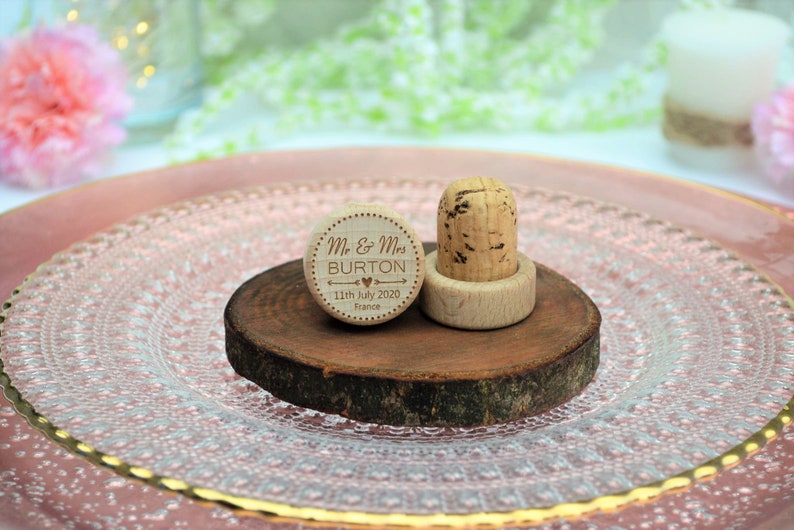 Personalized wine stopper, laser engraved, design 3, perfect for decorating rustic style weddings, parties and anniversaries. Made of wood and cork, on a table with decorative flowers. An excellent wedding favor for guests